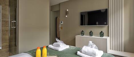 Ett hotellrum med en säng, en TV, en minibar och ett badrum med dusch.