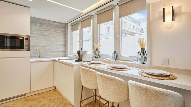 A modern kitchen with a built-in microwave, a sink, and bar stools.