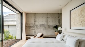 Un dormitorio moderno con una cama grande, una silla y vistas al exterior.