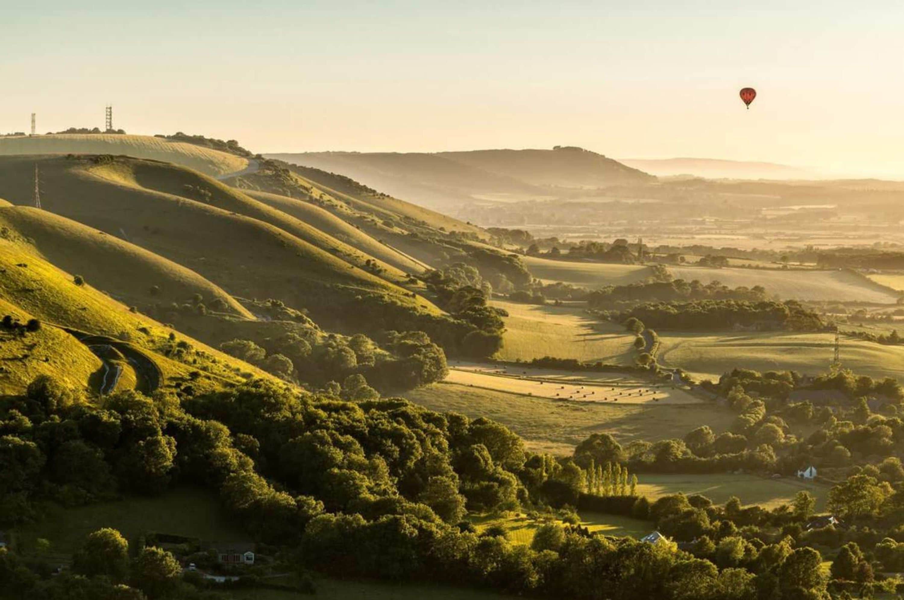Rolling hills with a hot air balloon in the distance.