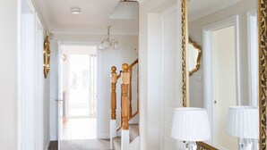 A hallway with a glass console table, a large mirror, and a chandelier. - Spacious 4-bed Seaside Retreat in Selsey (Chichester)