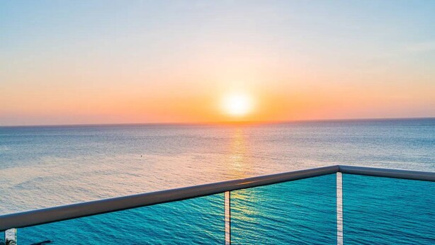A sunset over the ocean from a balcony with a view of the sea. - Majestic 3BR With Fantastic Pool in Bolivar (Santa Marta)