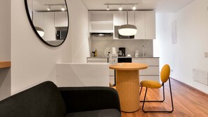 A modern kitchen with white cabinets, a round wooden table, and a yellow chair. - w Modern Loft w Brilliant Deco in Chapinero (Bogotá)