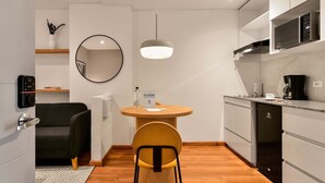 A modern kitchen with a round dining table, a black sofa, a mirror, and built-in appliances. - w Modern Loft w Brilliant Deco in Chapinero (Bogotá)