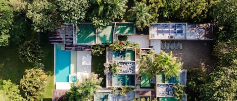 An aerial view of a resort with multiple buildings, a swimming pool, and lush greenery surrounding the property.