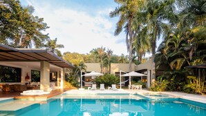 A modern pool area with lounge chairs and umbrellas, surrounded by palm trees and a covered seating area. - w Splendid 5BR Villa at Mesa de Yeguas (Anapoima)