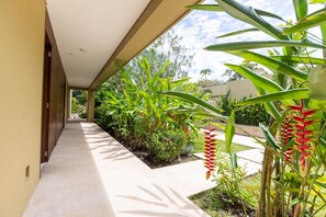 A covered walkway with a tiled floor, surrounded by lush greenery and plants. - w Beautiful 4BR Villa at Mesa de Yeguas (Anapoima)