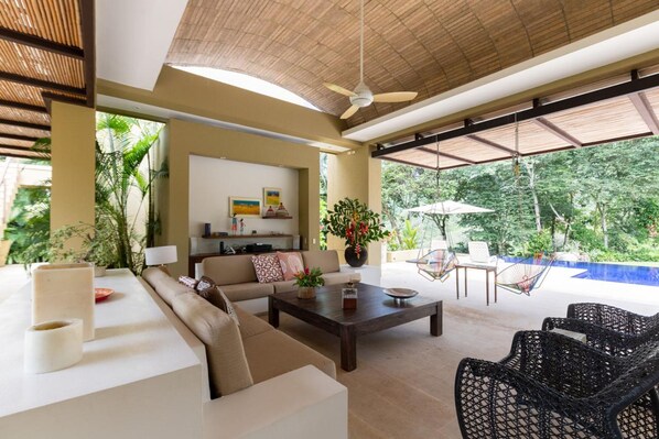 A spacious living area with a sofa, coffee table, and wicker chairs. A ceiling fan and a large window provide natural light. - w Beautiful 4BR Villa at Mesa de Yeguas (Anapoima)