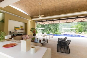 A spacious living area with a ceiling fan, a sofa, a coffee table, and a view of a swimming pool. - w Beautiful 4BR Villa at Mesa de Yeguas (Anapoima)