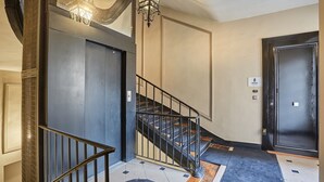 Un intérieur moderne avec un escalier, un lustre et une porte portant une inscription.