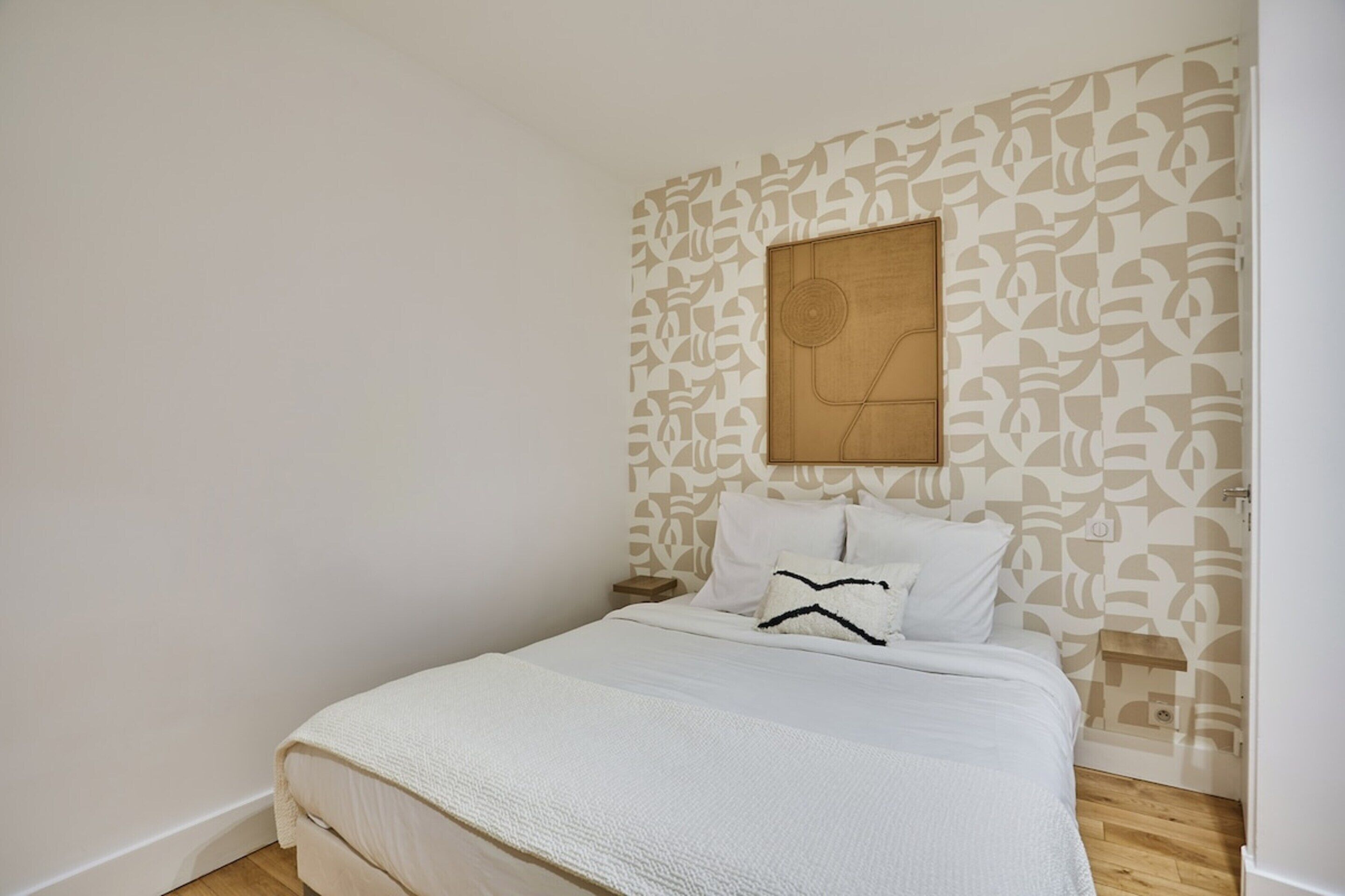 A bedroom with a bed, a nightstand, and a wall-mounted artwork.