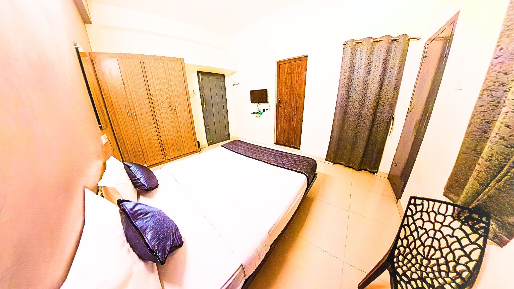 A room with a bed, a chair, a wardrobe, and a door.