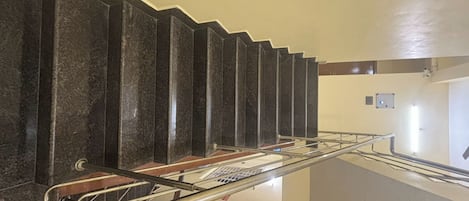 Un interno moderno con una scala, ringhiere in metallo e una parete di colore chiaro.