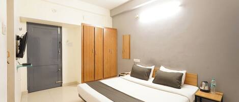 A hotel room with a bed, bedside table, wardrobe, and a ceiling fan.