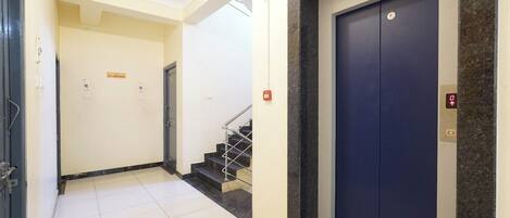 A hallway with a blue elevator, a staircase, and a sign indicating a non-smoking area.