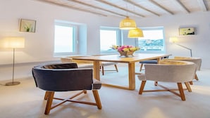 A modern dining area with a wooden table, chairs, and pendant lighting. - Elegant Villa With View (Mykonos)