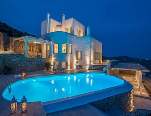 A modern villa with a pool, stone walls, and outdoor seating.