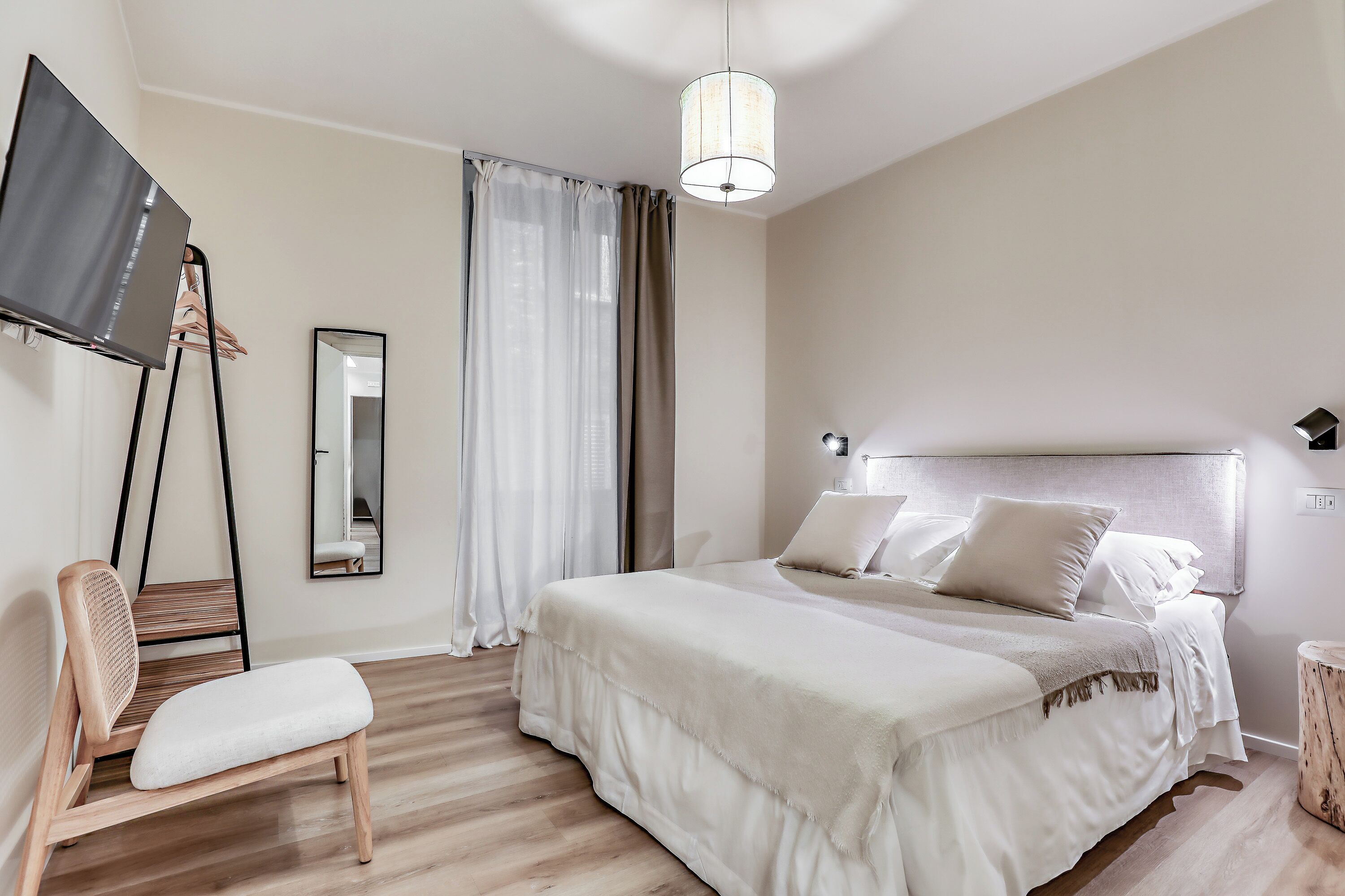 A bedroom with a bed, a chair, a TV, and a mirror.