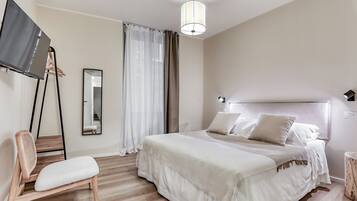 A bedroom with a bed, a chair, a TV, and a mirror.