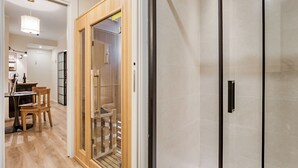 A hotel room with a wooden door, a glass partition, and a tiled wall. - Welchome suites (Perugia)