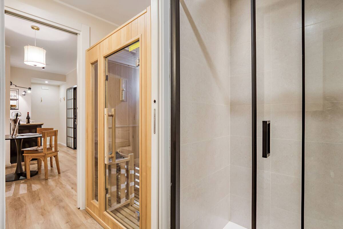 A hotel room with a wooden door, a glass partition, and a tiled wall.