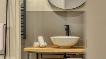 A bathroom with a wooden vanity, a white sink, and a round mirror.