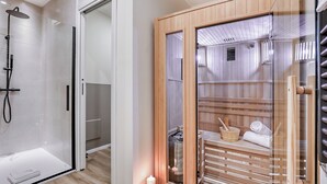 A modern bathroom with a glass-enclosed shower, wooden sauna, and a visible towel rack. - Welchome suites (Perugia)