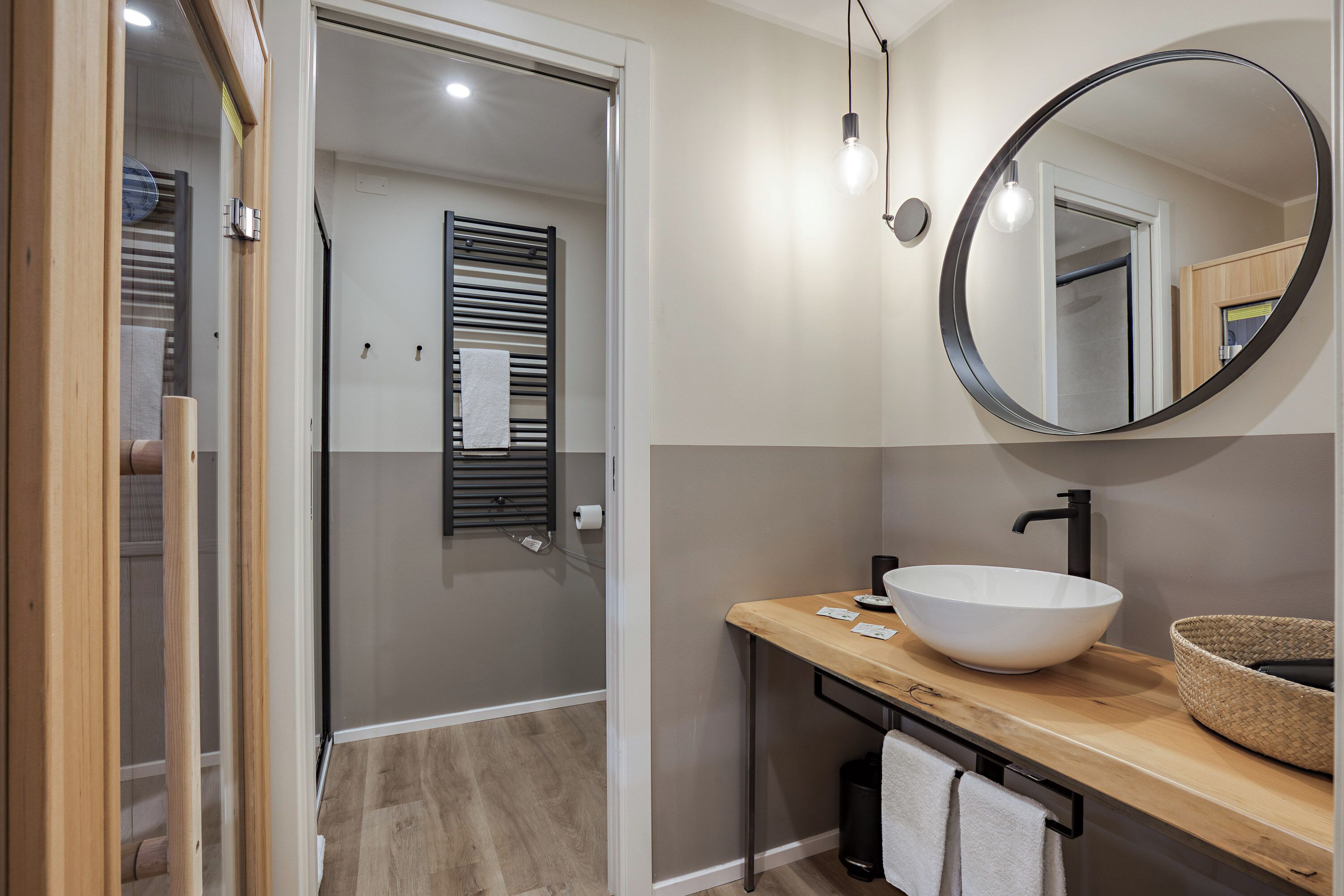 Een moderne badkamer met een houten wastafelmeubel, een grote spiegel en een inloopdouche.