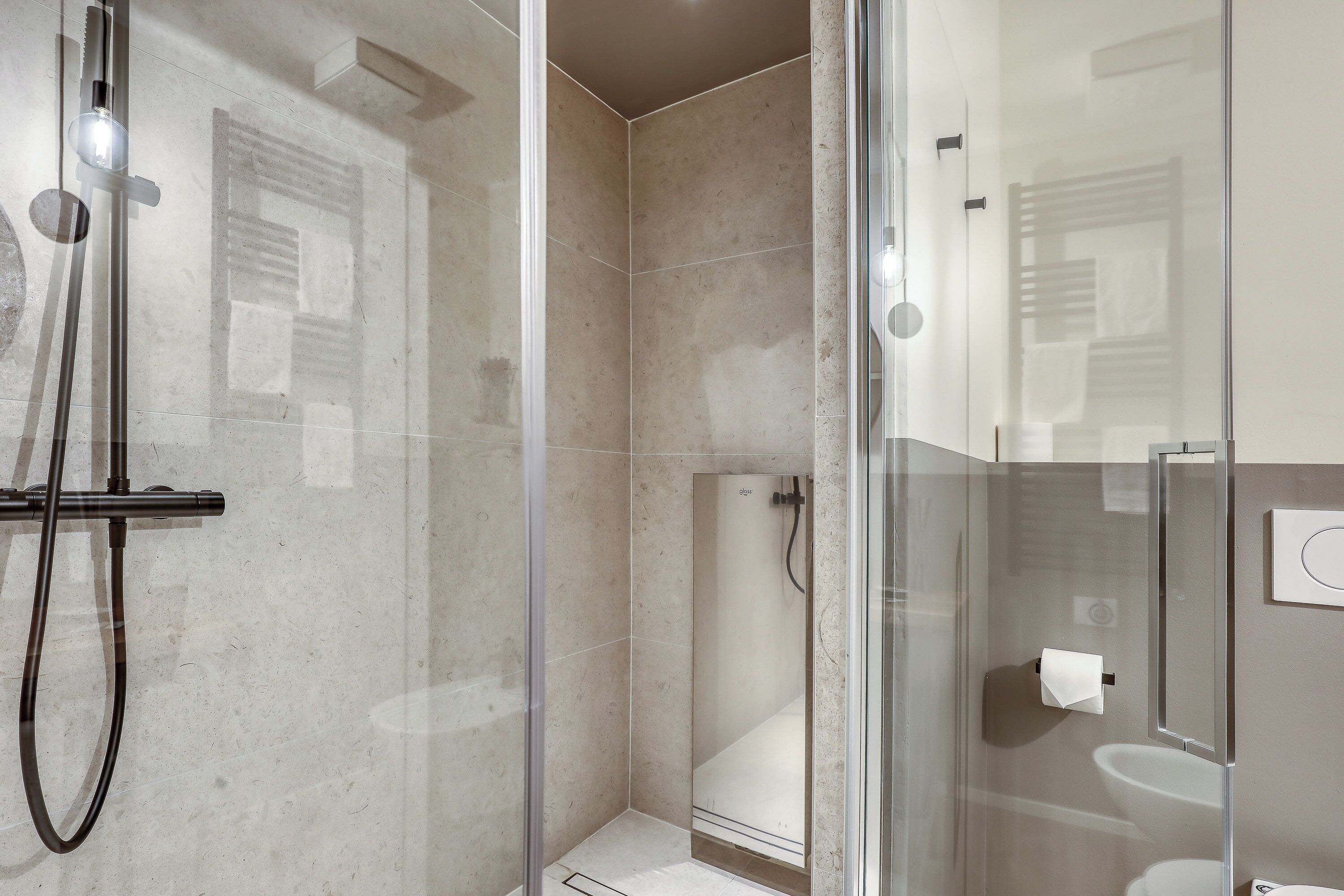 A modern bathroom with a glass-enclosed shower, a toilet, and a sink.