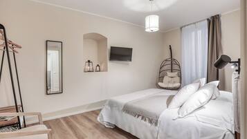 A bedroom with a bed, a hanging chair, a television, and a mirror.