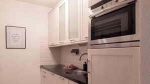 Una cocina moderna con armarios blancos, un horno de acero inoxidable y un lavamanos.
