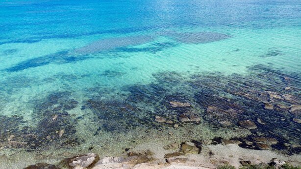 A clear view of a beach with visible underwater rocks and clear water. - Villa Laura by Wonderful Italy (Alghero)