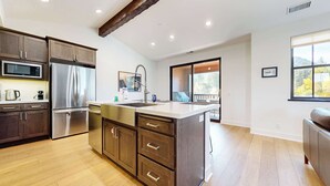 A modern kitchen with dark wood cabinets, stainless steel appliances, and a large island. - Spa & Gym Access | Near Lakes Basin | Sleeps 8 (Mammoth Lakes)
