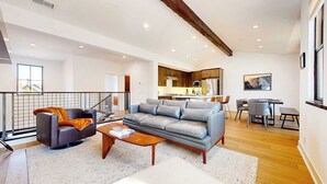 A modern living room with a grey sofa, a coffee table, and a dining area with a table and chairs. A kitchen is visible in the background. - Spa & Gym Access | Near Lakes Basin | Sleeps 8 (Mammoth Lakes)