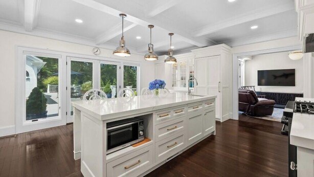 A spacious kitchen with white cabinetry, a central island with a built-in microwave, and pendant lighting. - Luxury rental with pool. Close to village and beach RPMS157 (Osterville)