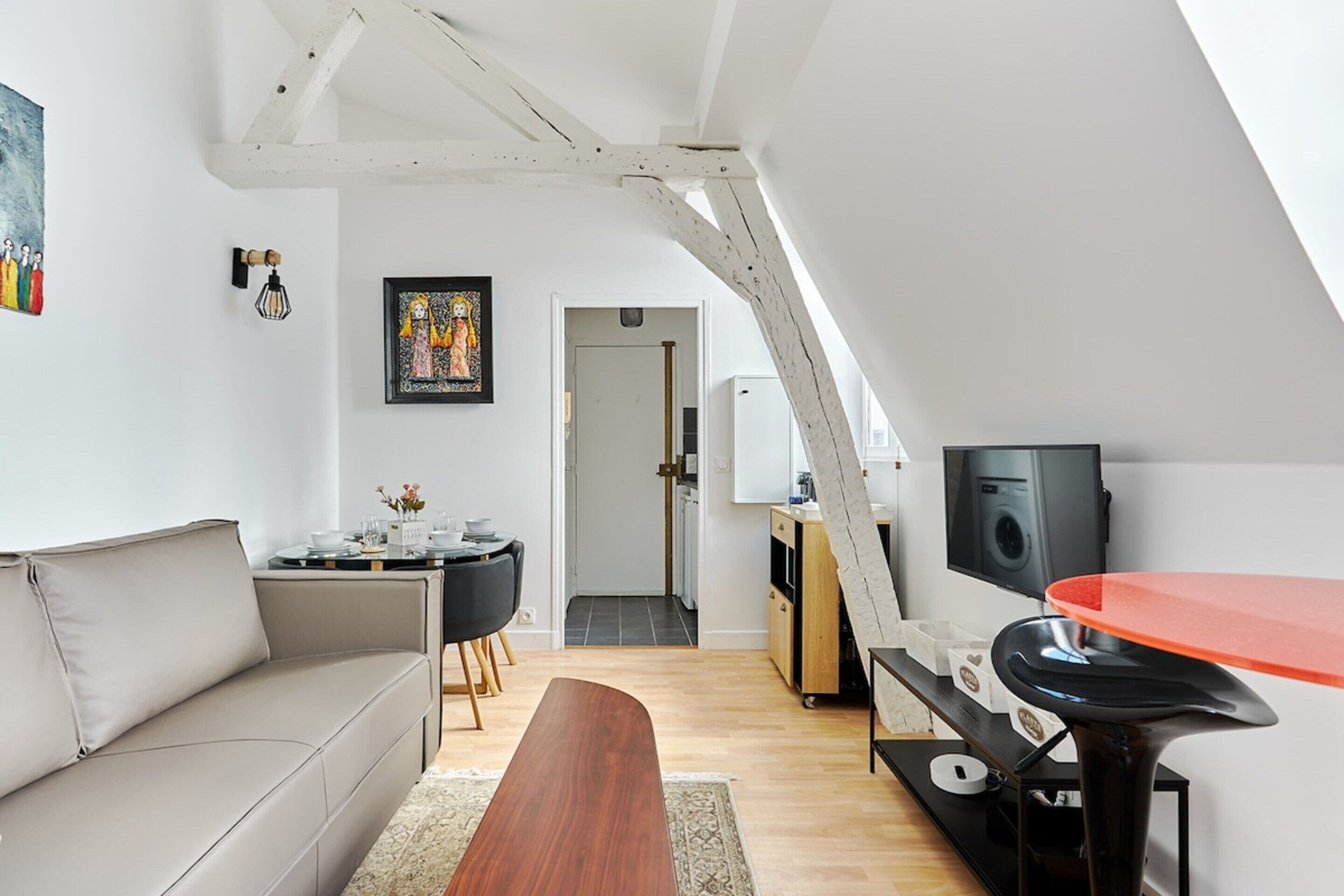 Un loft moderno con techos altos, un comedor, una cocina y una sala de estar con sofá y mesa de centro.