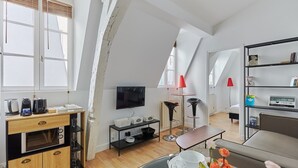 Een modern loft appartement met een keuken, een eettafel en een zithoek met een bank en een boekenkast.