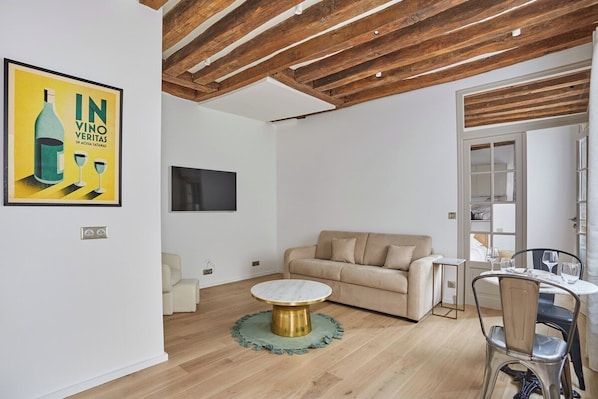 A modern living room with a round coffee table, a beige sofa, and a dining area with chairs and a table. - Eiffel Tower Apartment/invalide (Paris)