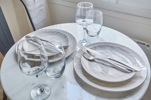 A table set with plates, cutlery, and wine glasses. - Eiffel Tower Apartment/invalide (Paris)