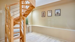 A wooden staircase with a handrail, a plant, and three framed pictures on the wall. - Charmant Duplex 1 Chambre Centre de Paris (Paris)