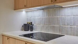 Eine Küche mit Holzschränken, einer gefliesten Spritzschutzwand und einer schwarzen Induktionskochplatte.