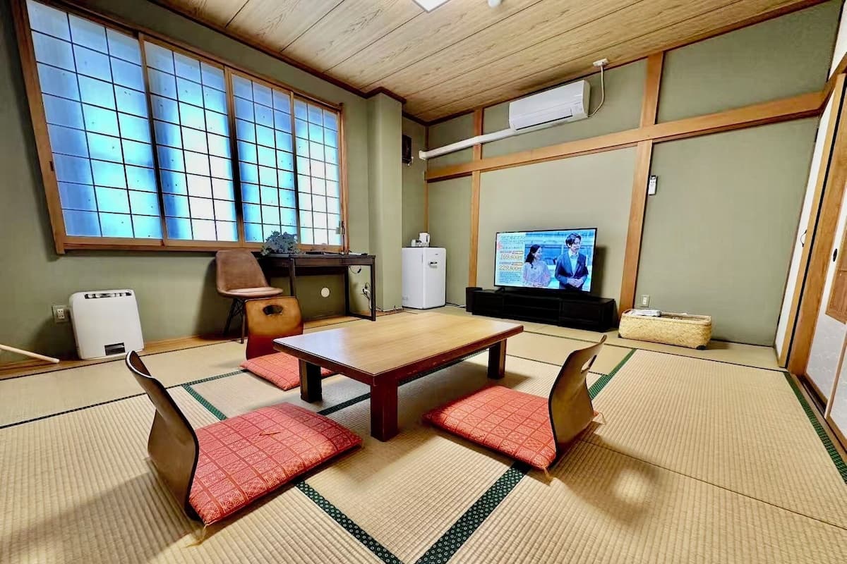Ein traditioneller japanischer Raum mit Tatami-Böden, einem niedrigen Holztisch und einem Fernseher.