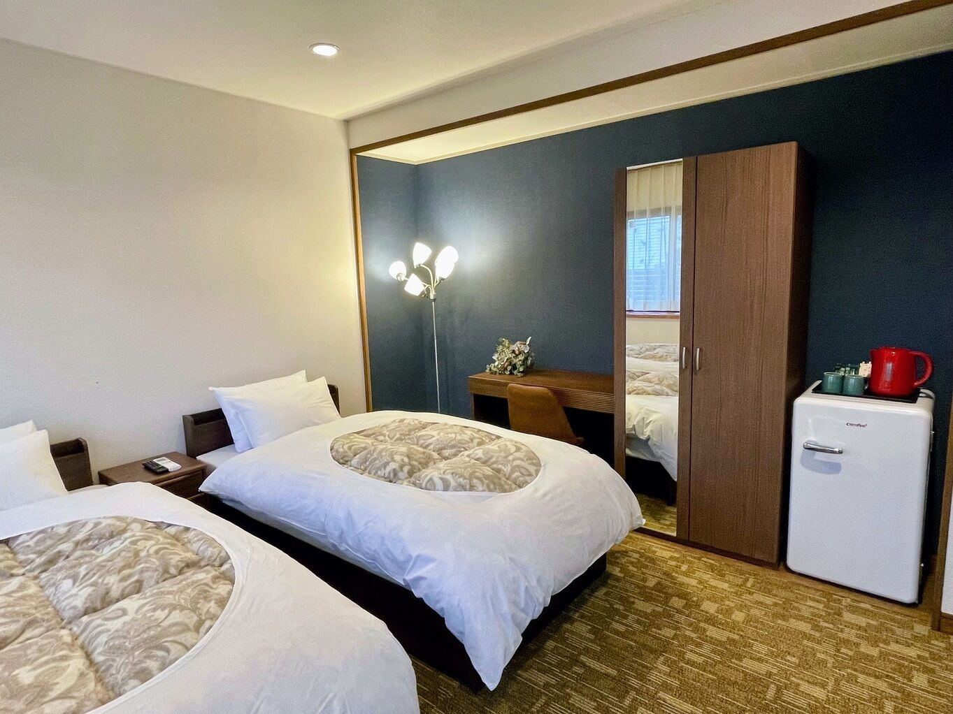 Une chambre d’hôtel avec deux lits, un bureau, une armoire et un mini-réfrigérateur.