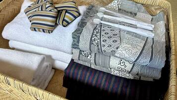 A wicker basket containing folded towels, a striped pillow, and a patterned cloth.