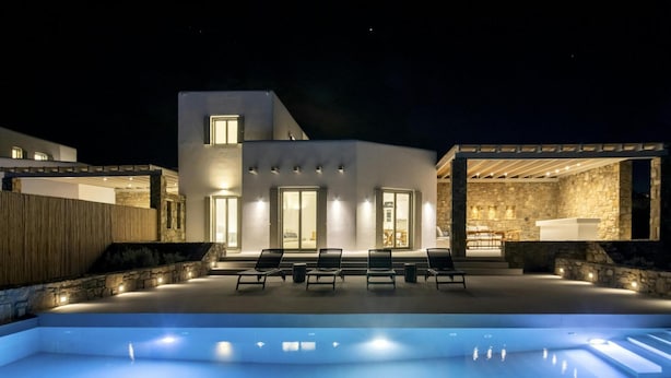 A modern house with a swimming pool, outdoor seating, and stone walls. - Pristine Villa With Swimming Pool (Mykonos)