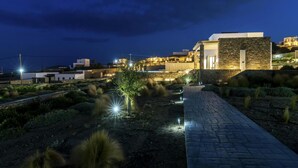 A modern building with a stone facade, a paved pathway, and surrounding greenery. - Pristine Villa With Swimming Pool (Mykonos)