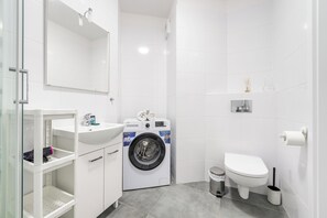 A modern bathroom with a built-in washing machine, a toilet, and a sink. - ShortStayPoland Żupnicza B83 (Warsaw)
