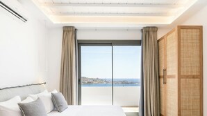 Ein modernes Schlafzimmer mit einem großen Bett, einem Kleiderschrank und Blick aufs Meer.