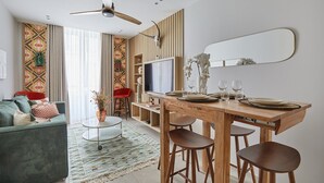 A modern living room with a sofa, coffee table, and a dining area with a wooden table and chairs.