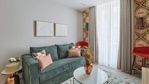 A modern living room with a green sofa, a round coffee table, and a large window with sheer curtains.